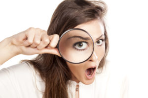 shocked young woman looking through a magnifying glass